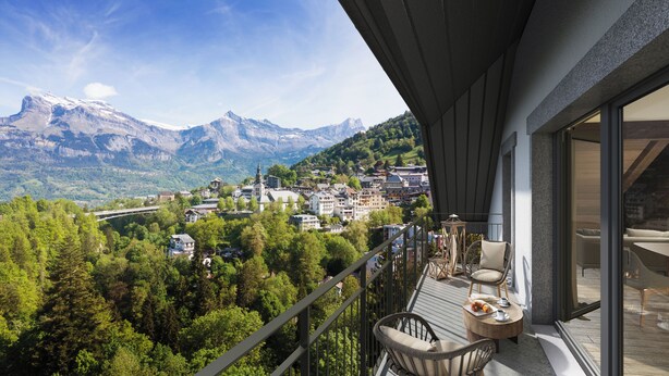 A balcony with a table, chairs, and a view of a mountain town. - TERRESENS - Les Sources de Canopée  (Saint-Gervais-les-Bains)