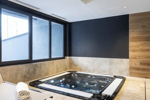 Un spa moderno con una bañera de hidromasaje grande, una ventana y una pared de madera.