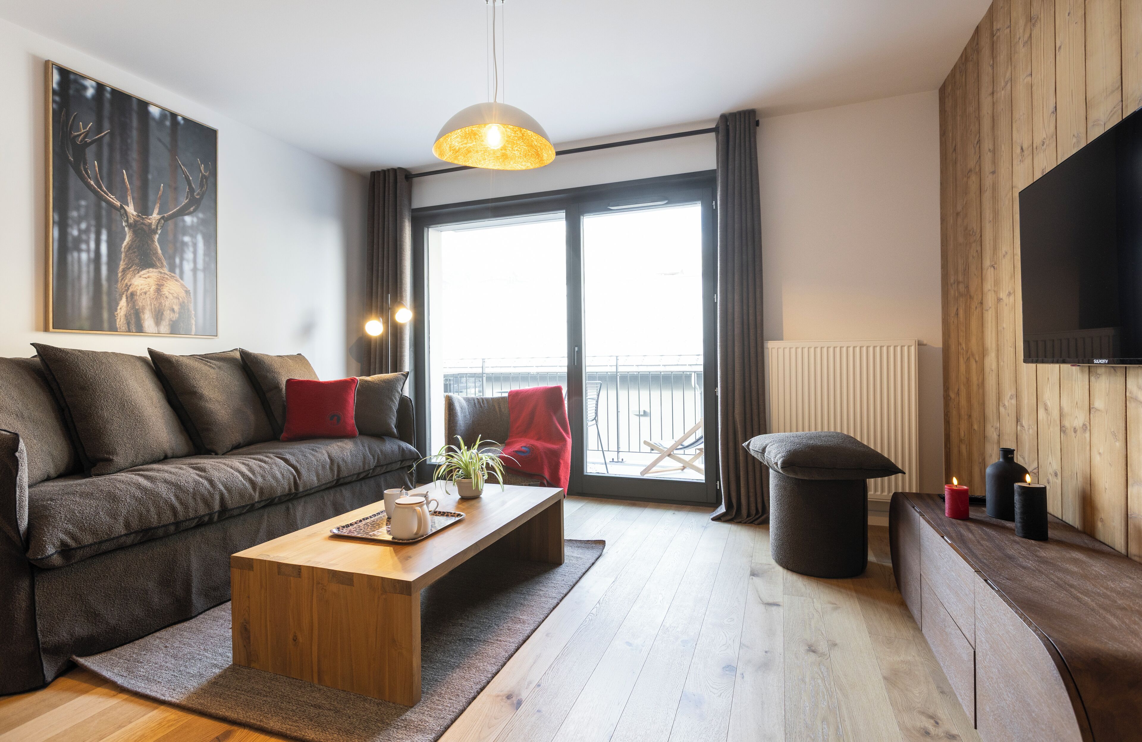 A modern living room with a sofa, coffee table, and a TV mounted on a wooden wall.