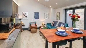 Eine moderne Küche mit Oberlicht, einem Essbereich mit Holztisch und einem blaugrünen Sofa.