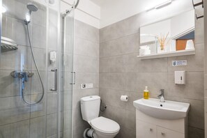 A modern bathroom with a glass shower enclosure, a white toilet, and a sink with a mirror above it. - Hotel Nowa Panorama Family Room & BB (Kraków)