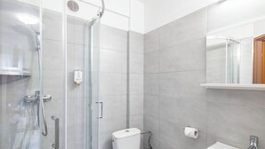 A modern bathroom with a glass-enclosed shower, a toilet, and a sink with a mirror above it.
