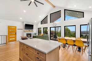 Una cocina moderna con una isla grande, armarios de madera y un comedor con sillas amarillas.