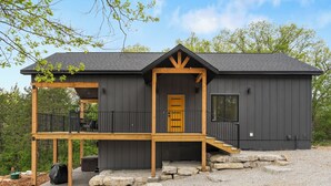 Une cabane à deux étages, dotée d’une terrasse en bois et de fondations en pierre.