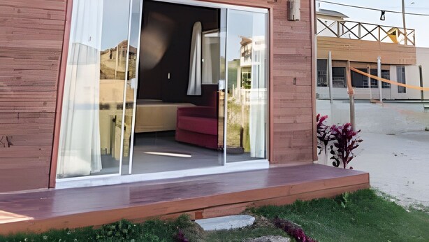 Ein modernes Haus mit einer großen Glasdoor, rotem Interieur und einem geneigten Dach.