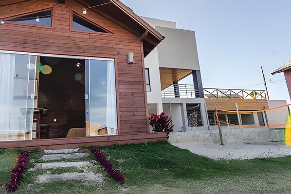 A modern two-story house with a large glass door and a small balcony. - Casa Ibiraquera - Praia do Rosa - SC 2 (Imbituba)