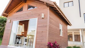 Ein modernes Holzhaus mit großem Schiebetüren-Eingang, einem sichtbaren Küchenbereich und einem kleinen Garten mit einer Pflanze.