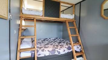 Una cama litera con una escalera, una ventana pequeña y un espejo en la pared.