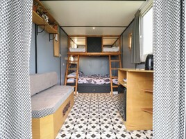 Una habitación compacta con una litera, un sofá, un escritorio pequeño y un suelo estampado.