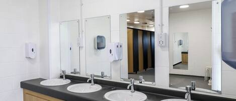 A modern bathroom with three sinks, wooden cabinets, and large mirrors.