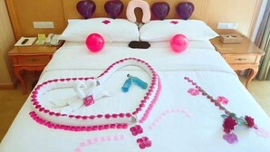 Et hotelværelse med en pænt redt seng, et natbord med telefon og lampe.