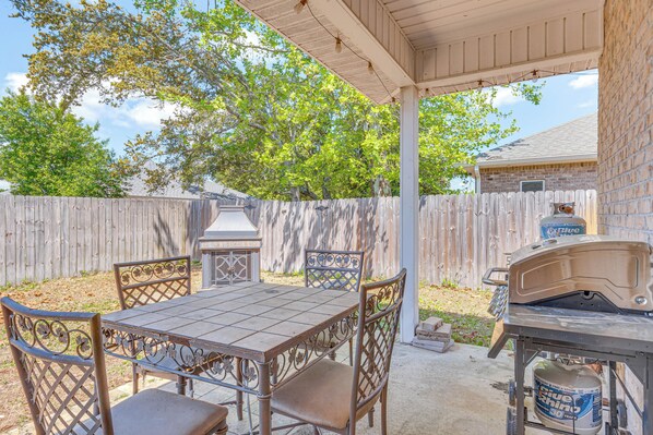 Une terrasse extérieure avec une table et des chaises en métal, un barbecue et une lanterne.