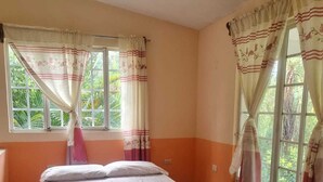 Habitación individual con ventana, cortinas y piso de baldosas.