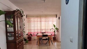 Un comedor con una mesa, sillas, un armario de madera y plantas en macetas.