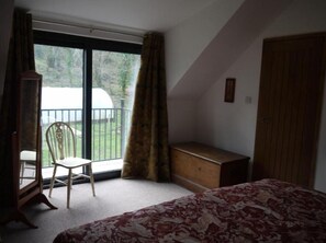 Enjoy a room with a large window, a comfortable bed, and a dresser, offering a view of the balcony.