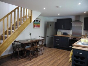 Efficient kitchen with a dining area, staircase, and wooden flooring.