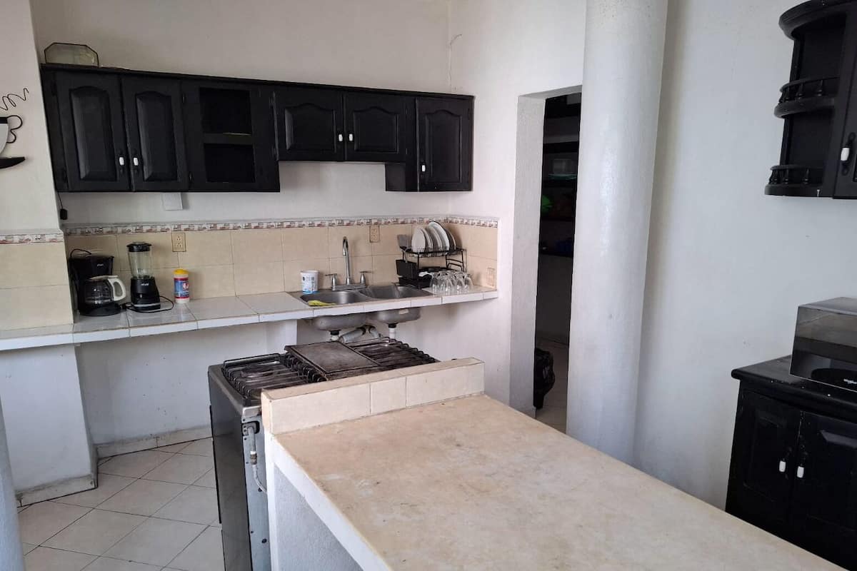 A compact kitchen with a stove, sink, and black cabinets.