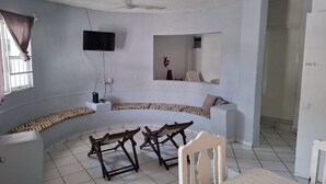 Ein Zimmer mit einer gebogenen Couch, einem kleinen Tisch und einem an der Wand befestigten Fernseher.