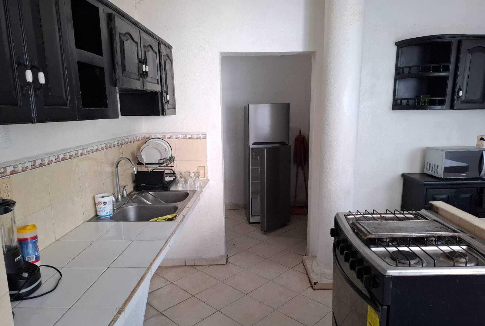 A kitchen with a sink, stove, refrigerator, and cabinets.