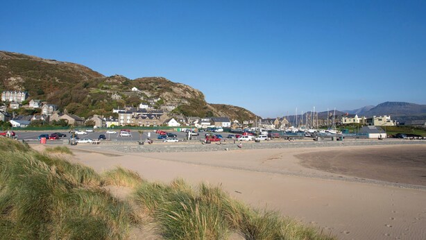 Un pueblo costero con edificios, una playa de arena y barcos.