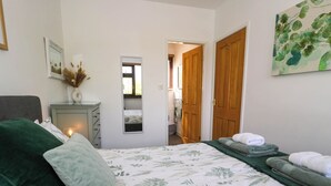 Un dormitorio con cama, cómoda, espejo y puerta que da a otra habitación.