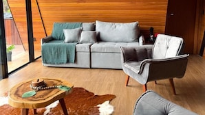 Ein modernes Wohnzimmer mit einem grauen Sofa, einem Holztisch und einem Ledersessel.