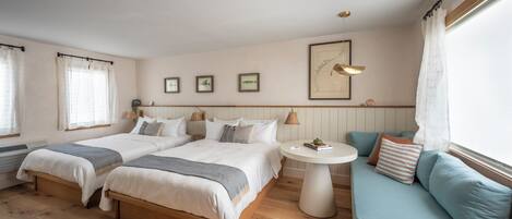 A bedroom with two beds, a round table, and a sofa.