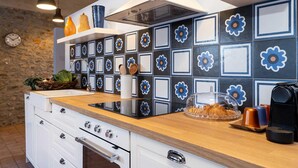 A modern kitchen with a wooden countertop, white cabinets, and a backsplash with blue and white tiles featuring flower designs. - Green Lodge - Apartment 1 - 1 BR 1 Bath (Cressa)