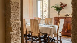 A dining room with a table set for four, surrounded by ornate chairs, a vase with flowers, and a wooden cabinet. - Palazzo Benassi Nobile (Asolo)