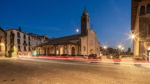 A historic building with a prominent tower and arched windows, situated in a cobblestone square with modern street lighting. - Palazzo Benassi Nobile (Asolo)