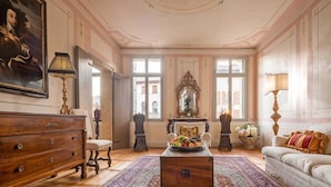A room with a wooden dresser, a chair, a table with fruit, a sofa, and a large mirror. - Palazzo Benassi Nobile (Asolo)