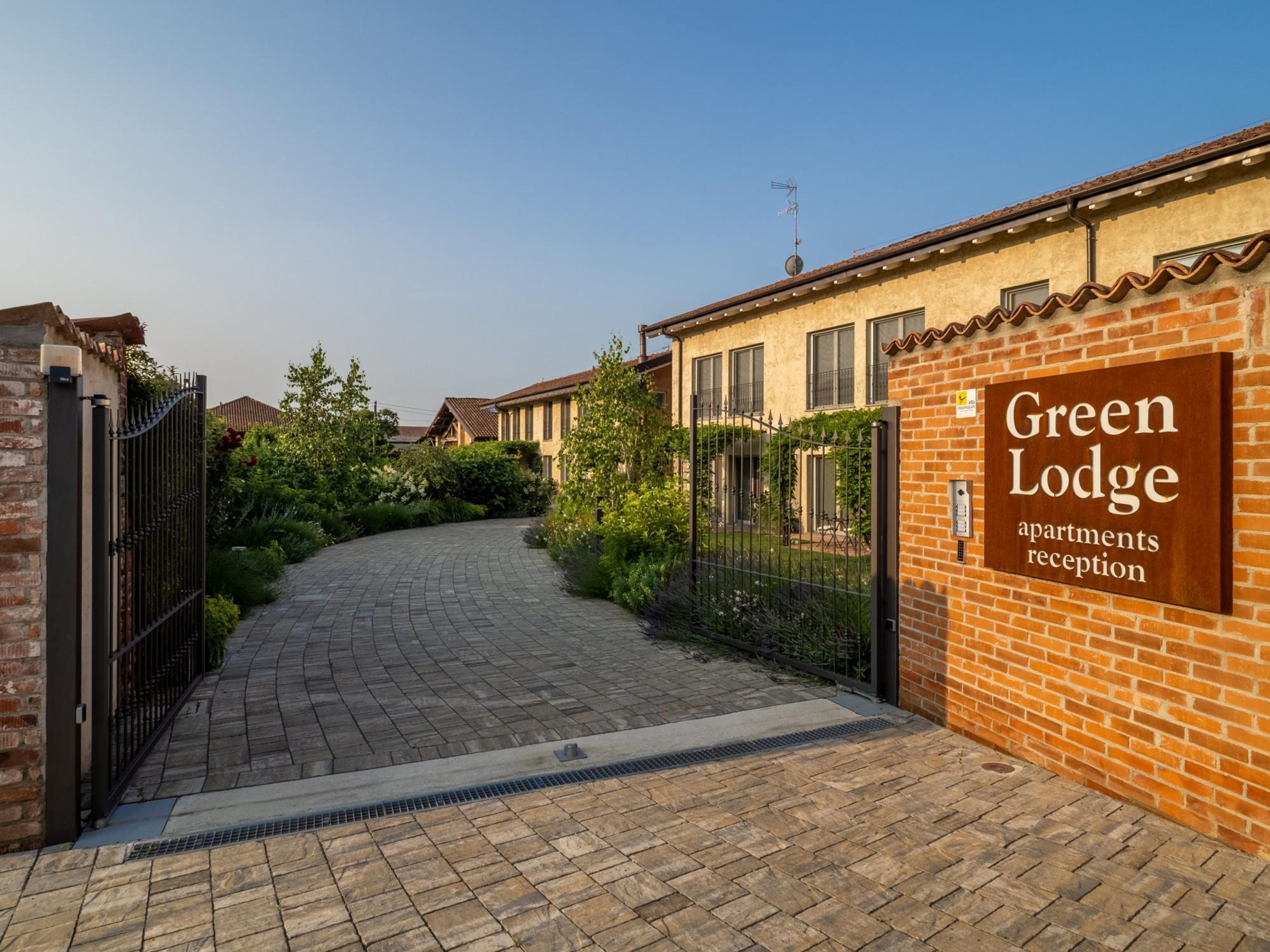 A brick building with a sign reading "Green Lodge apartments reception".