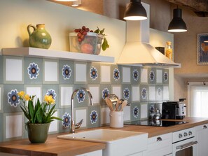 Una cocina con salpicadero de azulejos, un fregadero, una estufa y una campana extractora.