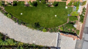 Vista aerea di un cortile con un prato curato, circondato da edifici con tetti in tegole e finestre.
