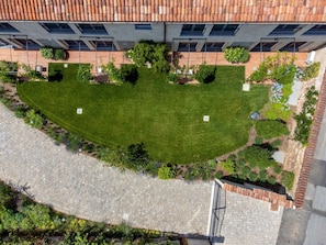An aerial view of a courtyard with a well-maintained lawn, surrounded by buildings with tiled roofs and windows. - Green Lodge - Apartment 5 - 1 BR 1 Bath (Cressa)