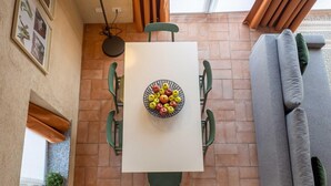 Zona pranzo con tavolo, sedie e una ciotola di frutta.