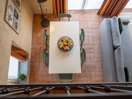 Un comedor con una mesa, sillas y un cuenco de fruta.