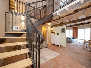 A spacious living area with a wooden staircase, a white cabinet, and a sofa.