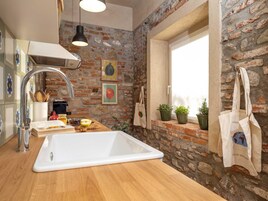 Una cocina con un lavamanos blanco grande, una lámpara colgante y una pared de ladrillo.