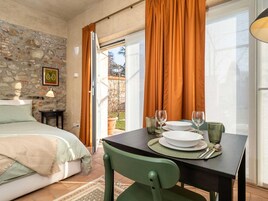 Una habitación con cama, una mesa dispuesta para comer y vistas a través de una puerta de cristal.