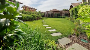 Un jardin bien entretenu, avec un chemin de pierres menant à une maison.