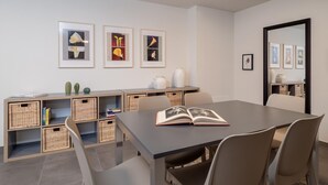 Un espace repas moderne comprenant une table, des chaises et une bibliothèque agrémentée de paniers en osier.