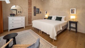 A bedroom with a large bed, a white dresser, a mirror, and a skylight. - Green Lodge - Apartment 9 - 2 BR 1 Bath (Cressa)