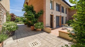 A courtyard with a brick building, potted plants, and outdoor seating. - Green Lodge - Apartment 9 - 2 BR 1 Bath (Cressa)