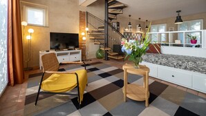 Una sala de estar moderna con piso a cuadros, un sofá, un televisor y una escalera.