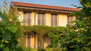 Un edificio con tejado de baldosas, un jardín con sendero de piedra y abundante vegetación.