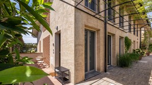Un edificio con un patio central, que cuenta con un área de descanso con mesa y sillas, y un pequeño jardín con plantas en macetas.