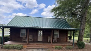 A log cabin with a porch, two rocking chairs, and a door.