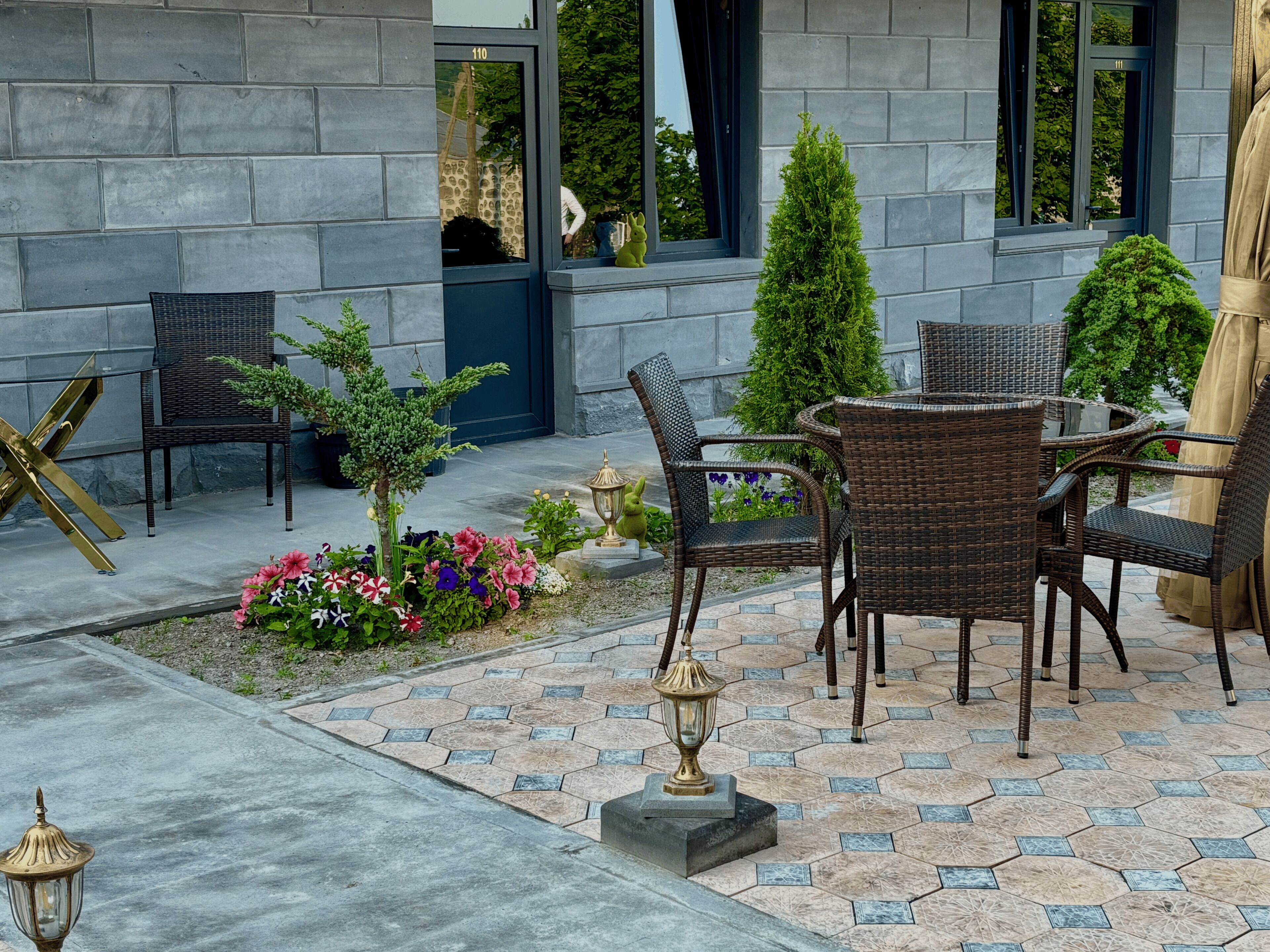 An outdoor patio with wicker furniture, a small garden, and a statue.
