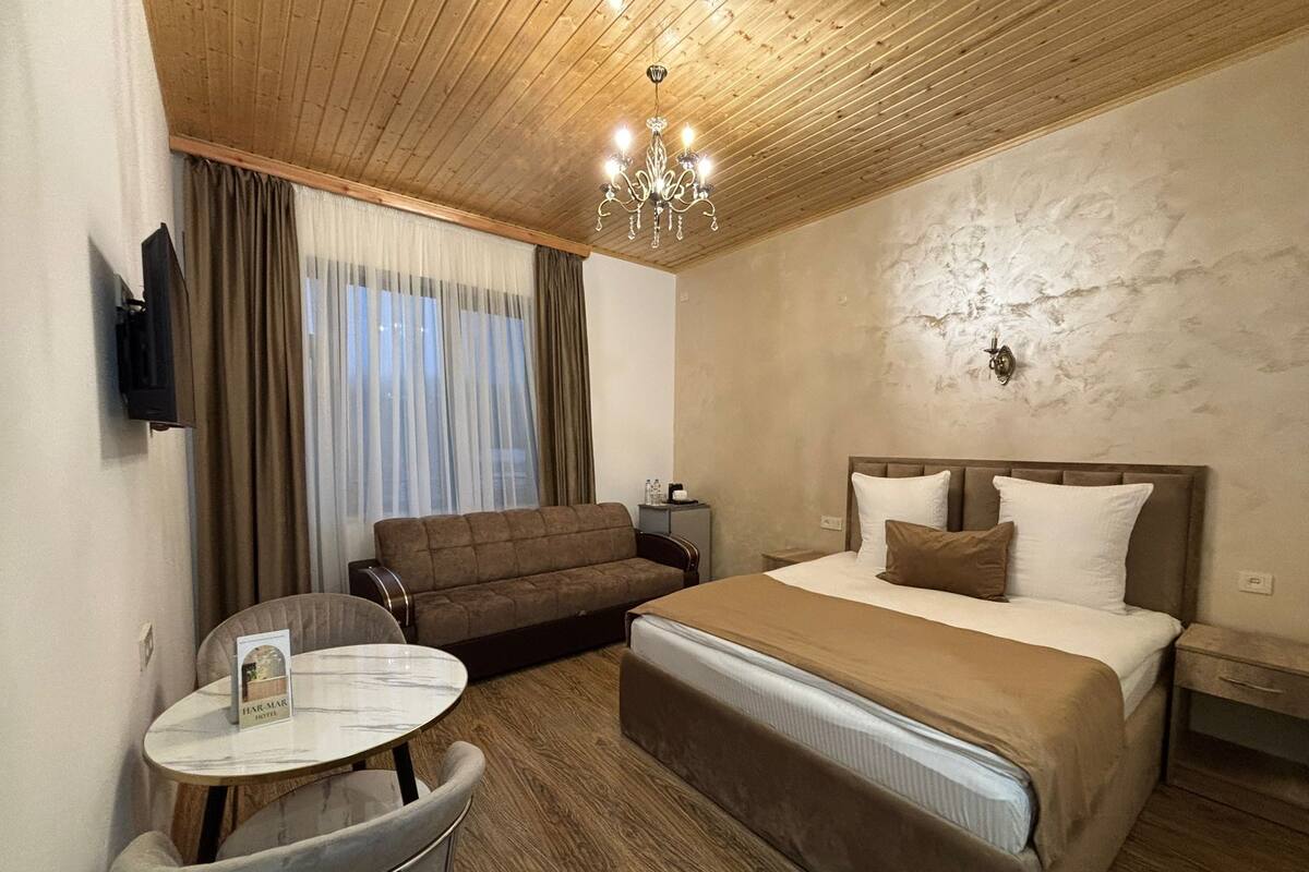 A hotel room with a bed, a sofa, a small table, and a TV.